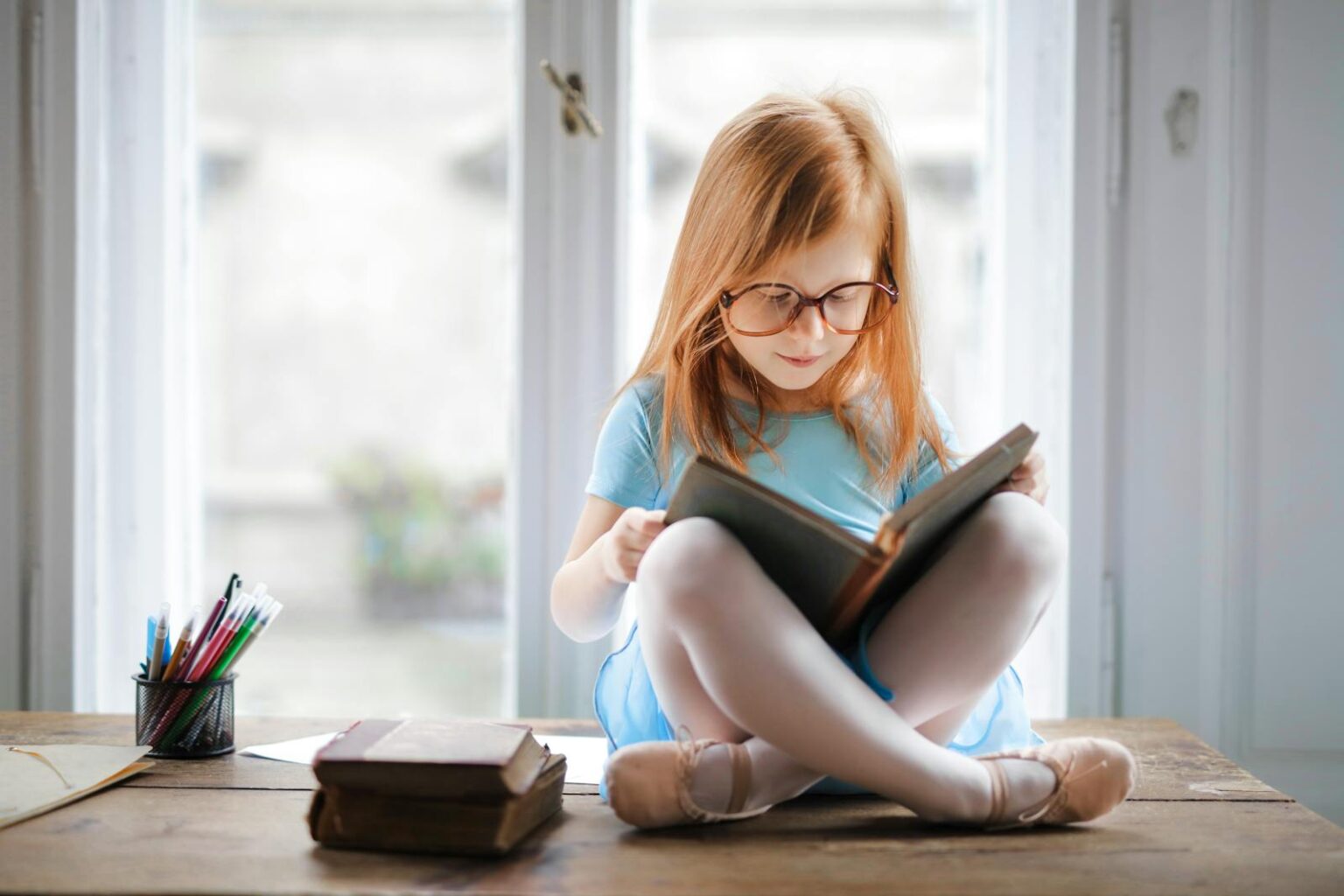 Jeune fille portant des lunettes et lisant un livre, illustration d'un comportement possible de trouble DYS.