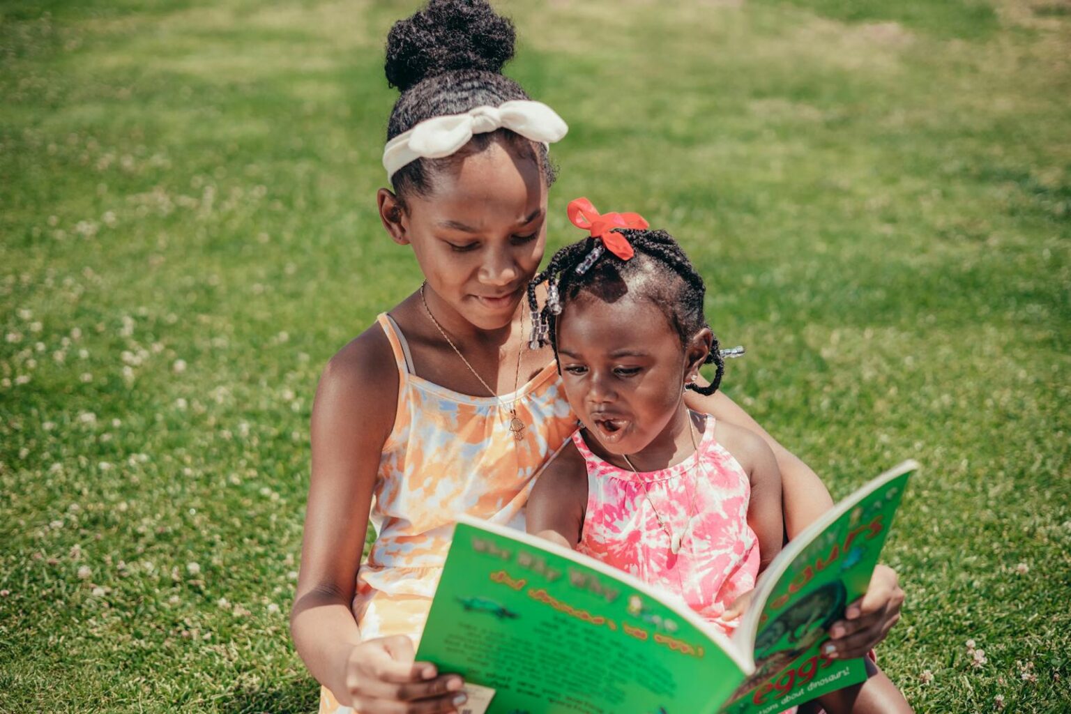 Deux jeunes filles lisant un livre ensemble dans un parc ensoleillé, respectant leur biorythme.